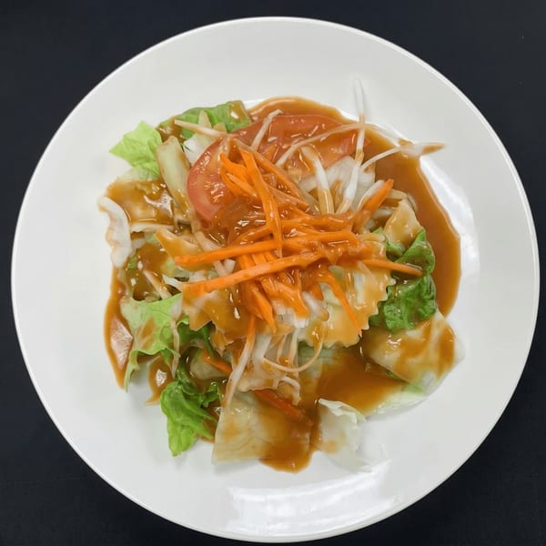 A fresh garden salad with lettuce, shredded carrots, tomatoes, and onions, drizzled with dressing.