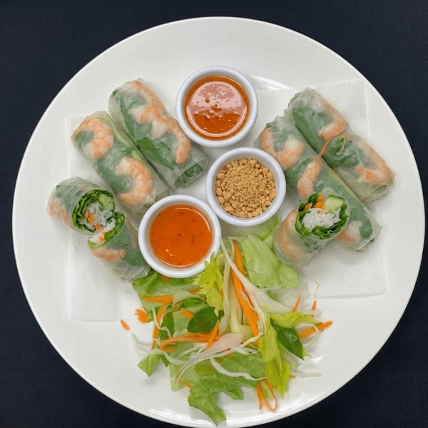 Fresh shrimp spring rolls with dipping sauces and a side salad on a white plate.